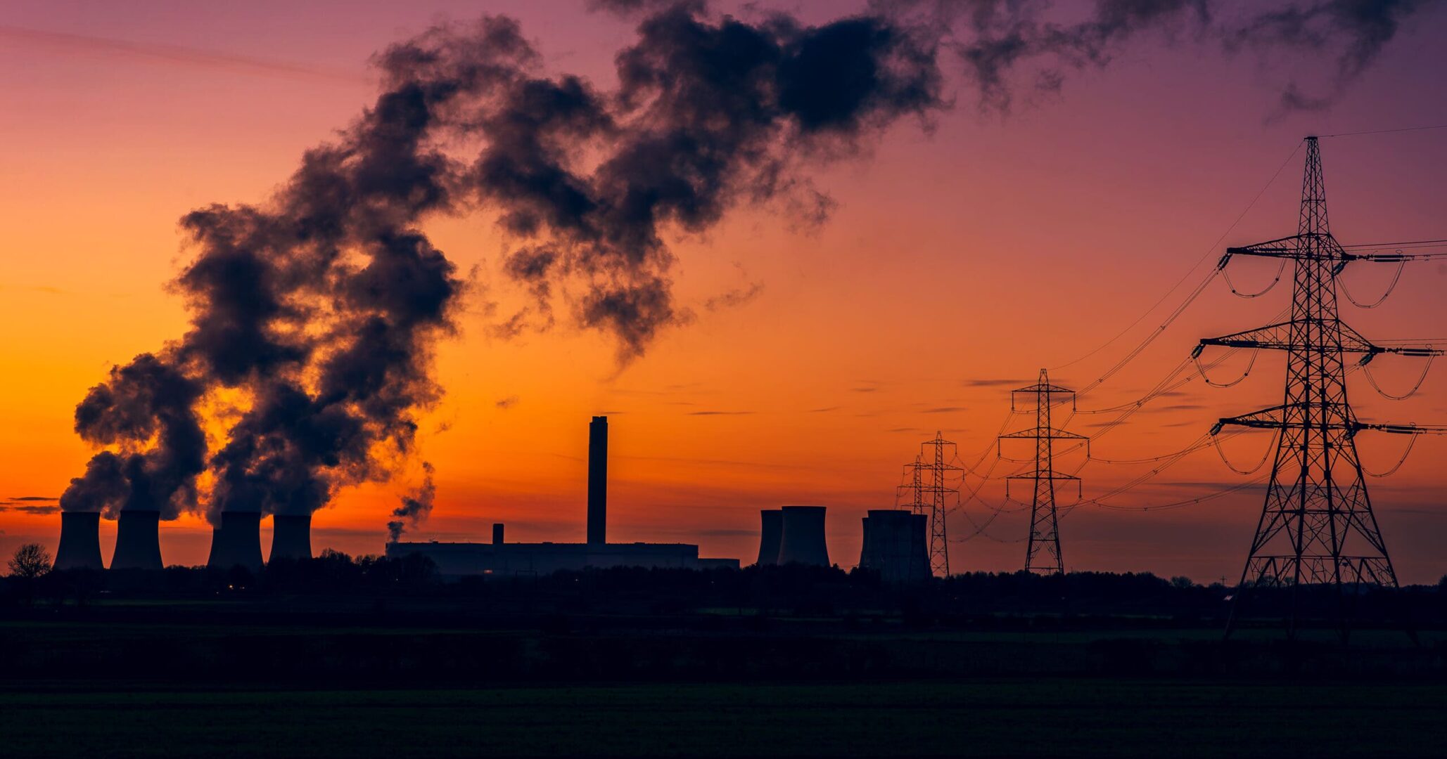 silhouette-of-a-power-stations-cooling-towers-against-a-beautiful-winters-sunset-near-drax-in-north-yorkshire-uk-with-electricity-pylons-and-plumes-of-water-vapour-rising-from-the-cooling-towers